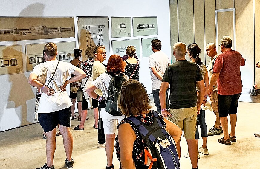 Gäste betrachten Bauzeichnungen. 